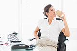 Relaxed businesswoman drinking a coffee at her desk