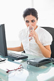 Focused businesswoman drinking a glass of water at her desk