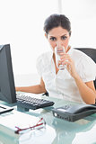Stern businesswoman drinking a glass of water at her desk
