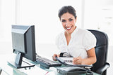 Happy businesswoman arranging her diary at her desk