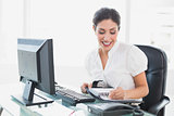 Happy businesswoman arranging her agenda at her desk