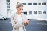 Frowning stylish businesswoman sending a text