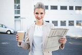 Smiling stylish businesswoman holding newspaper and coffee