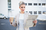Stern stylish businesswoman reading newspaper