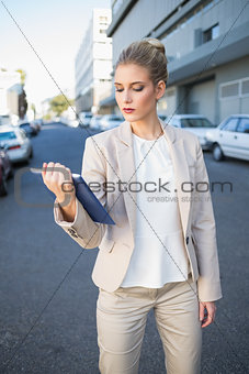 Stern classy businesswoman holding tablet computer