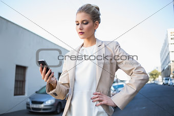Serious elegant businesswoman looking at her smartphone