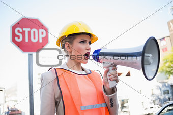 Businesswoman wearing builders clothes shouting in megaphone