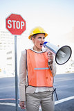 Angry businesswoman wearing builders clothes shouting in megaphone