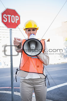 Businesswoman wearing builders clothes screaming in megaphone
