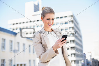 Cheerful attractive businesswoman sending a text message