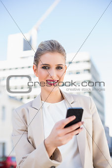 Cheerful gorgeous businesswoman sending a text message