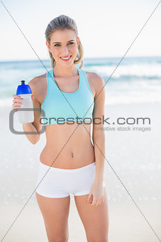 Cheerful sporty blonde in sportswear holding flask