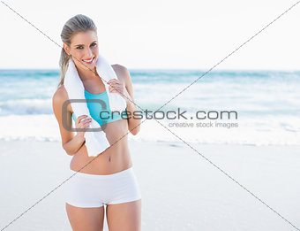 Smiling sporty blonde in sportswear with towel around neck