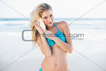 Sexy gorgeous blonde in bikini holding shell by her ear