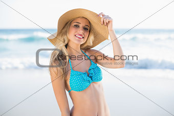 Cheerful sexy blonde in bikini wearing straw hat