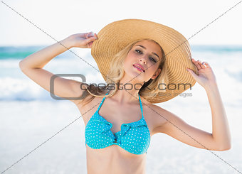 Peaceful sexy blonde in bikini wearing straw hat