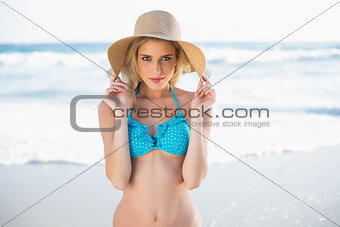 Peaceful sexy blonde in bikini playing with her straw hat