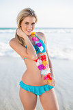 Cheerful sexy blonde in bikini wearing hawaii necklace