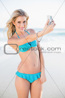 Smiling sexy blonde in bikini taking a self picture
