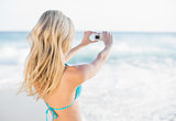 Rear view of attractive blonde in bikini taking a self picture