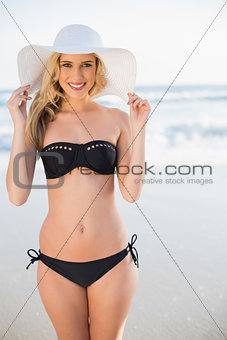 Smiling sexy blonde in elegant bikini wearing straw hat