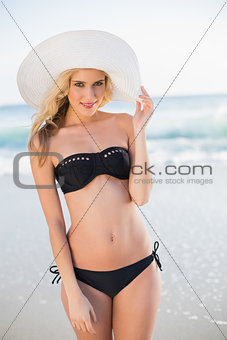 Smiling sexy blonde in elegant bikini wearing straw hat posing