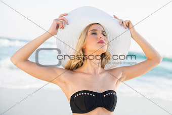 Relaxed sexy blonde in elegant bikini wearing straw hat posing