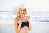 Relaxed blonde in elegant black bikini wearing straw hat posing