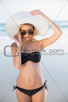 Stern blonde in elegant black bikini posing