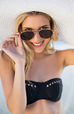 Smiling blonde in elegant black bikini looking over her sunglasses