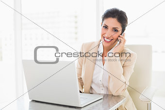 Happy businesswoman working with a laptop on the phone