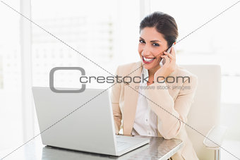 Smiling businesswoman working with a laptop on the phone