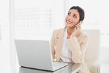 Cheerful businesswoman working with a laptop on the phone