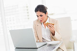 Focused businesswoman eating lunch as she is working