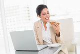 Happy businesswoman eating lunch as she is working
