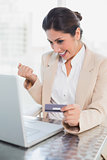 Excited businesswoman shopping online with laptop