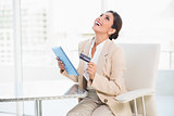 Laughing businesswoman shopping online with tablet pc