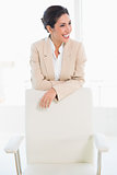 Happy businesswoman standing behind her chair