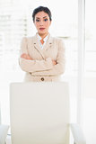 Serious businesswoman standing behind her chair