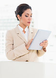 Businesswoman standing behind her chair using digital tablet