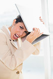 Crazed businesswoman hitting head off laptop looking at camera