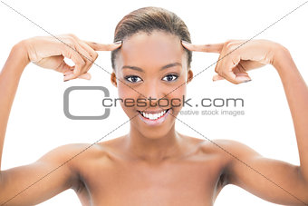 Cheerful natural beauty pointing at forehead