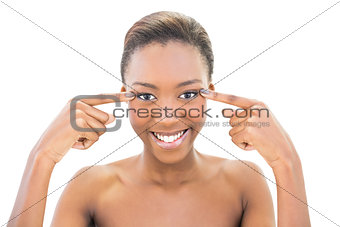 Smiling beautiful model pointing at her eyes