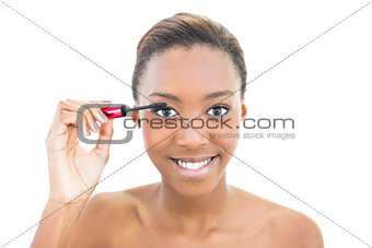 Smiling beautiful model applying mascara