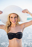 Smiling sensual blonde in elegant black bikini wearing straw hat