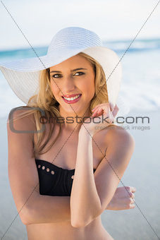 Cheerful sensual blonde in elegant black bikini wearing straw hat