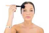 Woman applying powder brush on forehead