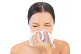 Brunette woman sneezing in a tissue