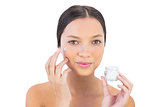 Attractive woman spreading beauty cream on her cheek