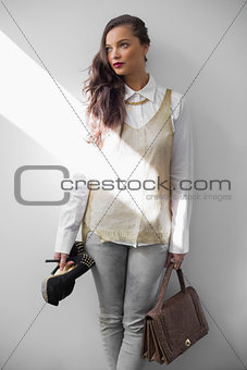Sensual trendy woman holding heels and handbag